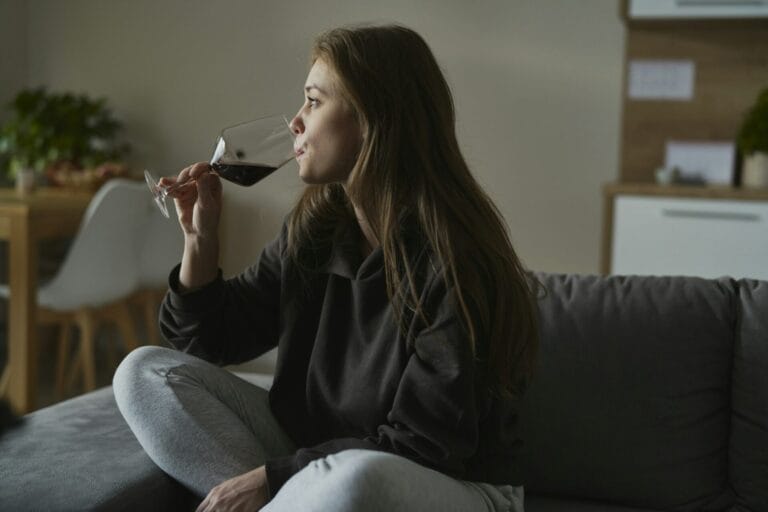 Caucasian woman with alcoholism drinking wine alone at home